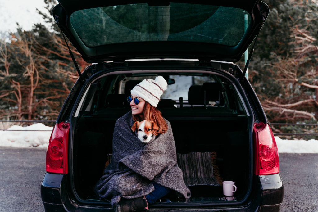 woman and cute jack russell dog enjoying outdoors at the mountain into the car. Travel concept. winter season