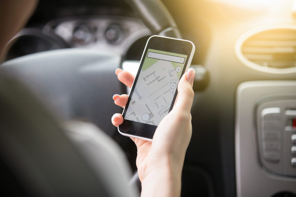 Close up of traveler female hand holding her phone with navigation system. Young woman traveling by car, trying to find the shortest route to a certain destination